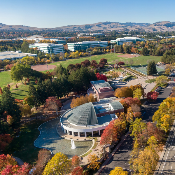 Aerial view of a campus with fall foliage and distant hills.