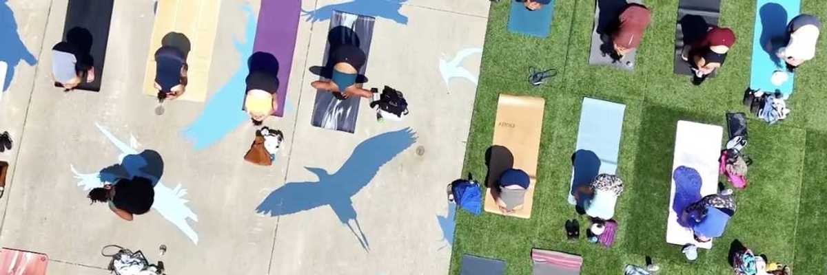 an aerial photo of people doing yoga on different colored mats outside