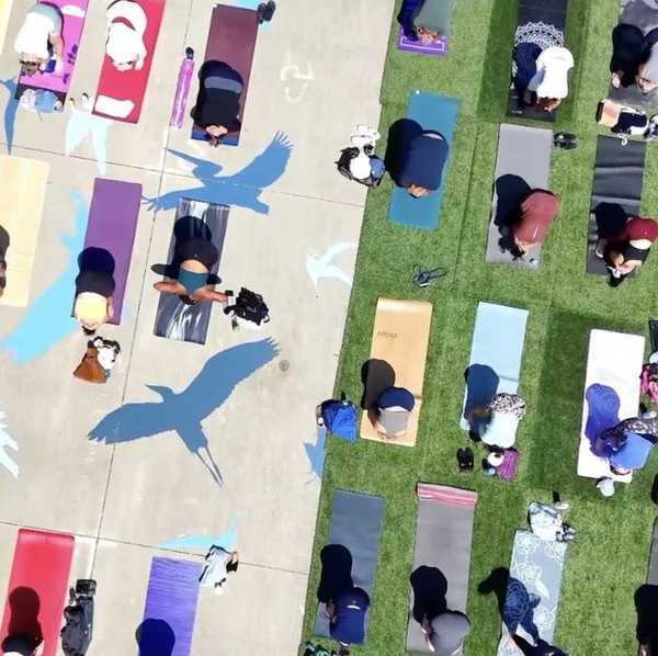 an aerial photo of people doing yoga on different colored mats outside