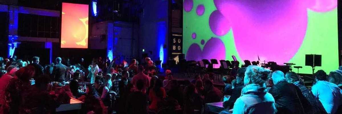 an auditorium full of people with a screen with colorful imagery