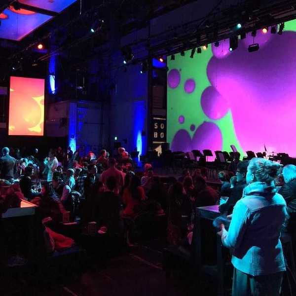 an auditorium full of people with a screen with colorful imagery