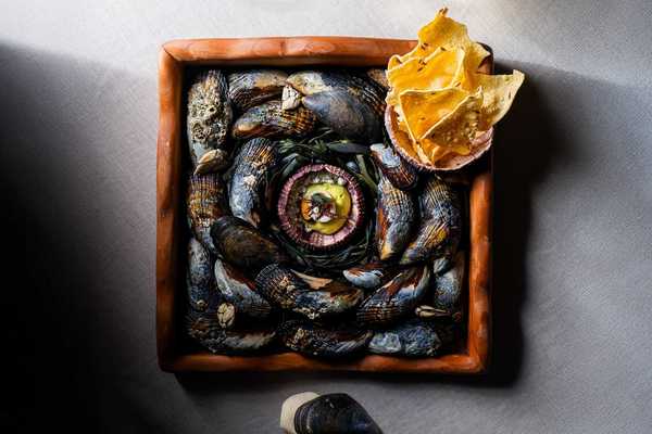 an elaborate tray of mussel shells with a fine dining bite positioned on top