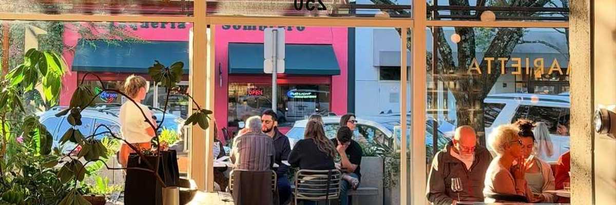 an open doorway with people sitting inside and outside on a patio