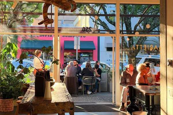 an open doorway with people sitting inside and outside on a patio