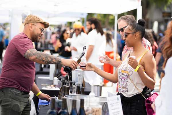 an outdoor event where wine is being poured for someone in line at a table