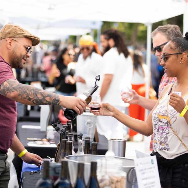 an outdoor event where wine is being poured for someone in line at a table
