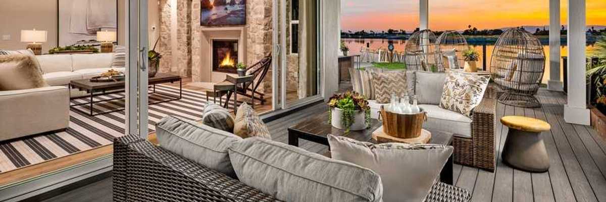 An outdoor patio on the water with comfy seating and a sunset