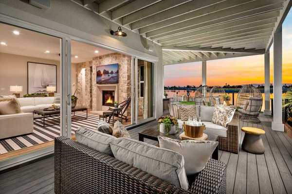 An outdoor patio on the water with comfy seating and a sunset