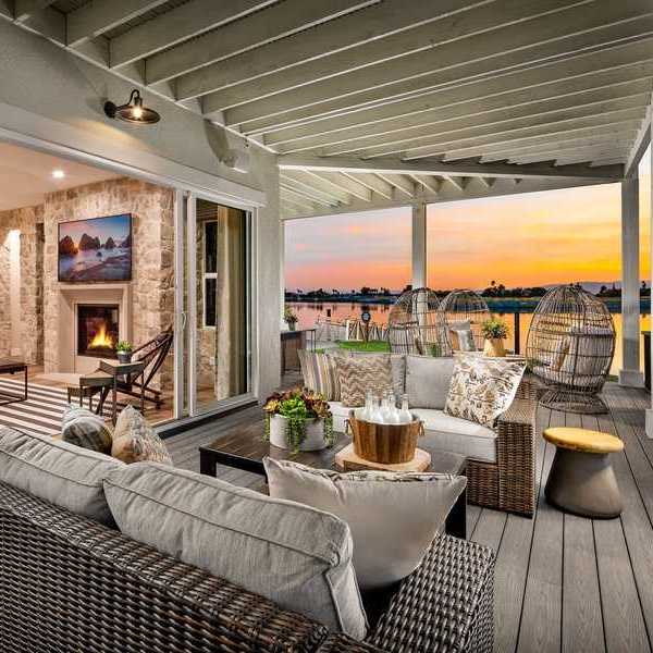 An outdoor patio on the water with comfy seating and a sunset