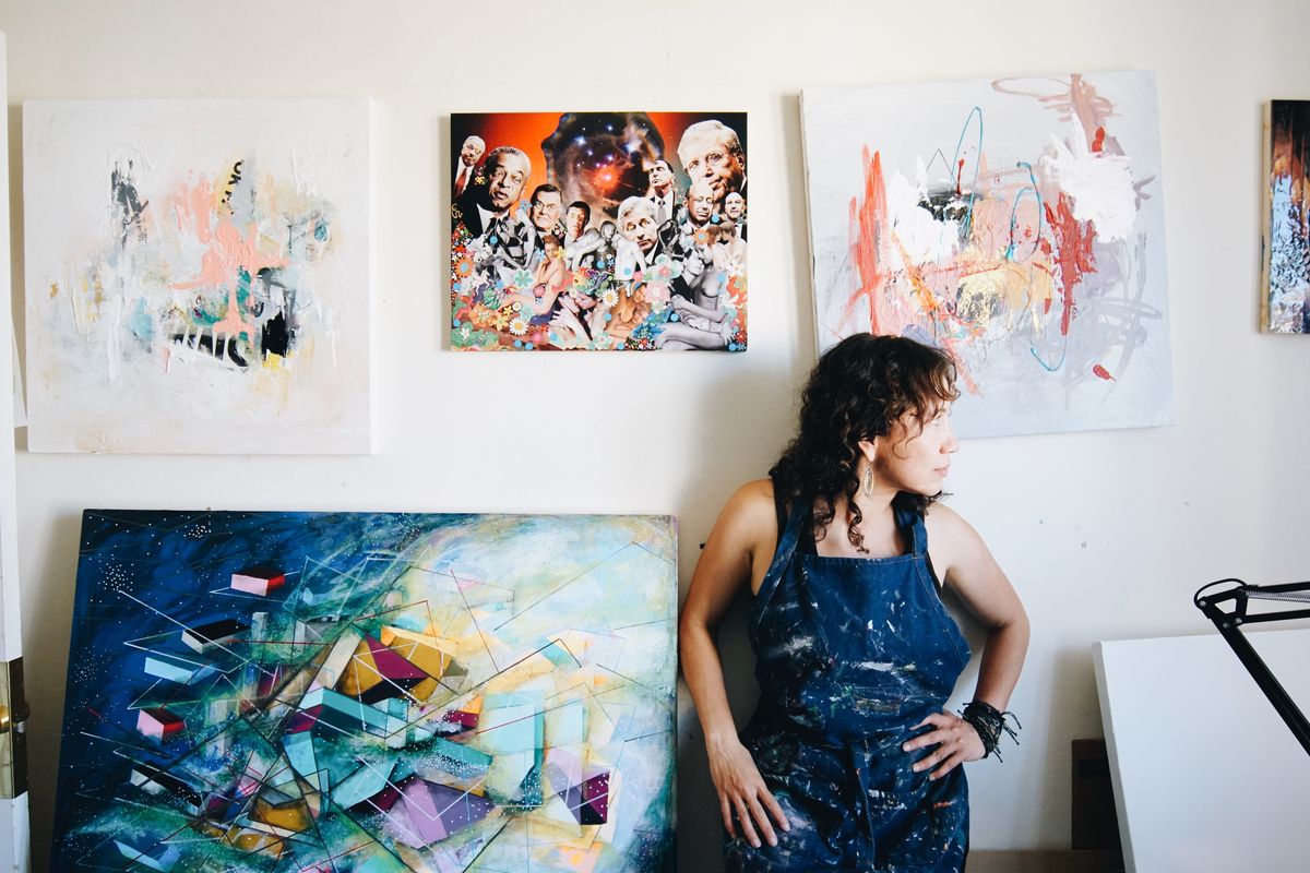 Artist in a studio with colorful abstract paintings on the walls.