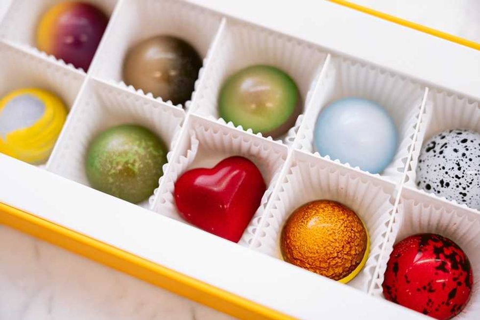 Assorted colorful chocolates in a box with varied shapes and designs.