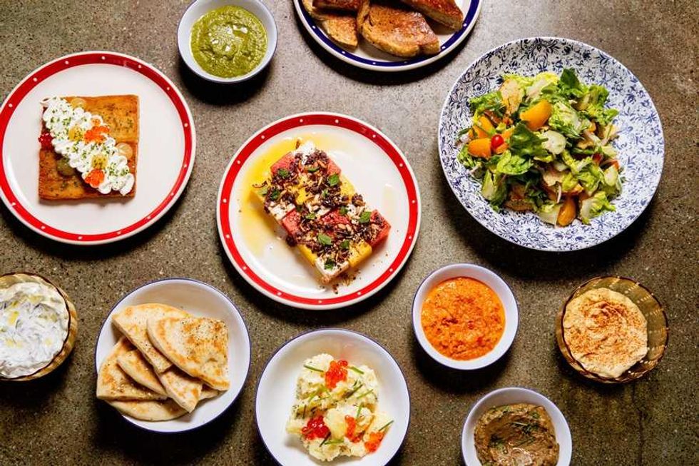 Assorted dishes and condiments on a table, featuring salads, dips, breads, and garnished plates.