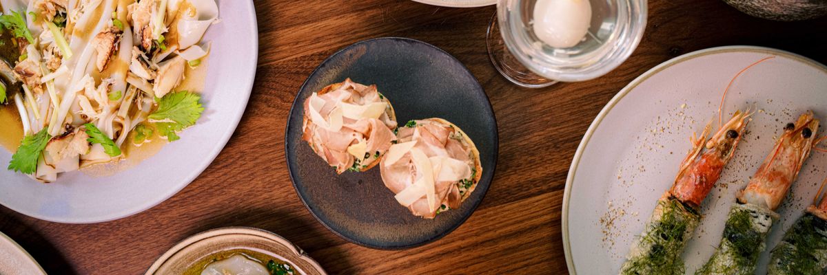 Assorted gourmet dishes with shrimp, noodles, and cocktails on a wooden table.