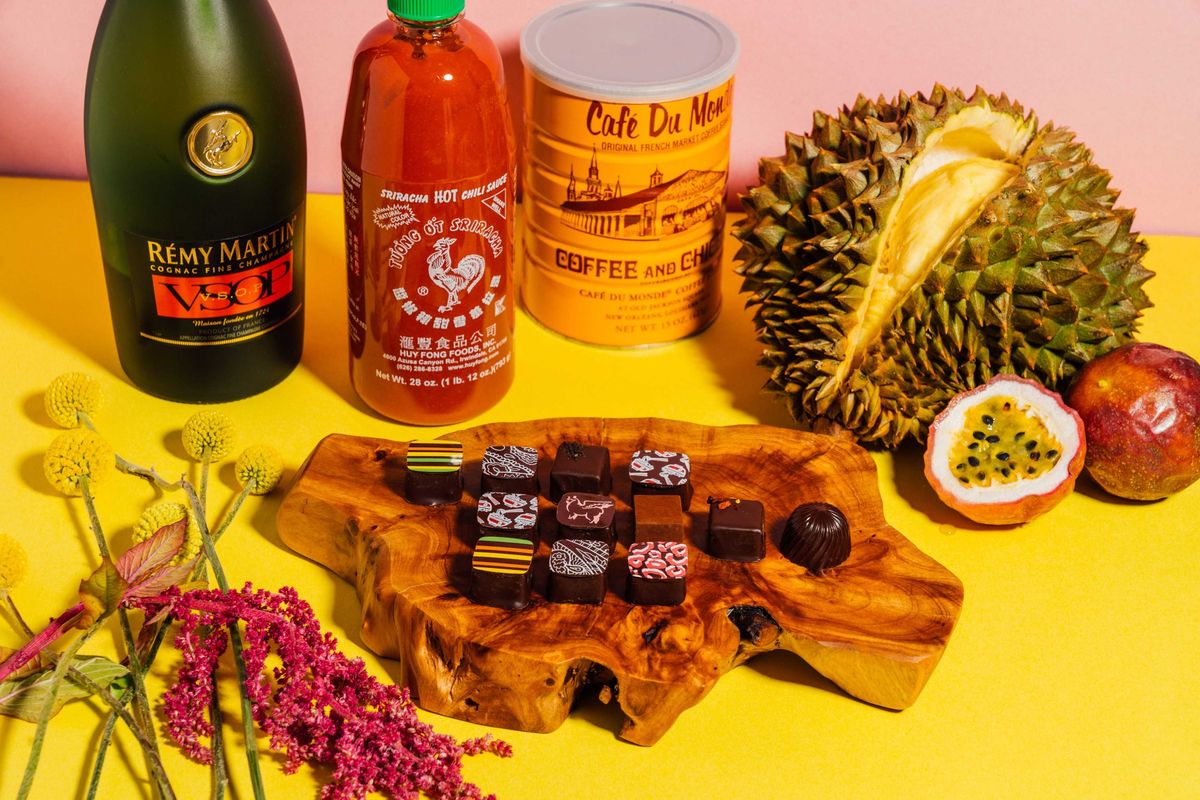 Assorted gourmet items: cognac, hot sauce, coffee, durian, passion fruit, chocolates, flowers.