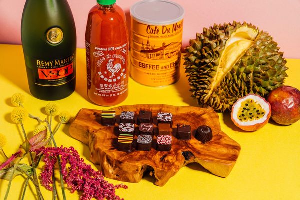 Assorted gourmet items: cognac, hot sauce, coffee, durian, passion fruit, chocolates, flowers.