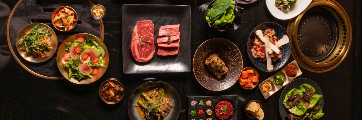 Assorted Korean BBQ dishes and sides on a dark table, ready for grilling.