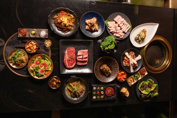 Assorted Korean BBQ dishes and sides on a dark table, ready for grilling.