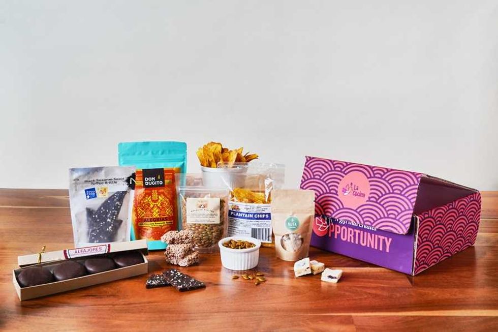 Assorted snacks displayed on a table beside a purple "La Cocina" box.