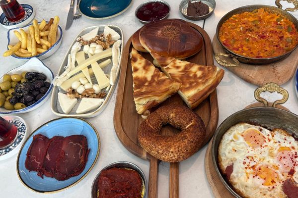 Assorted Turkish breakfast spread with breads, cheeses, olives, tea, and fried eggs.