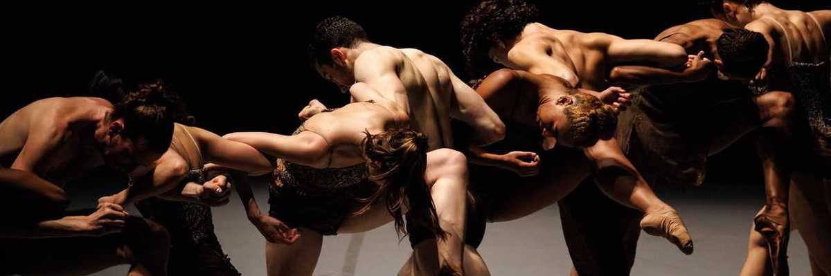 ballet dancers intertwined on a dark stage