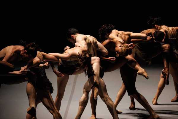 ballet dancers intertwined on a dark stage
