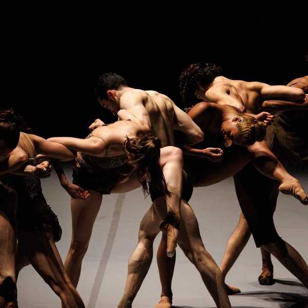ballet dancers intertwined on a dark stage