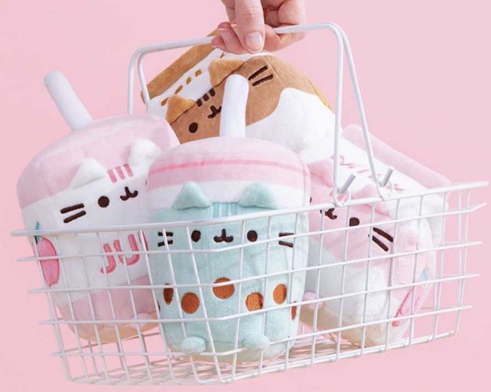Basket of plush bubble tea toys with cute cat designs against a pink background.