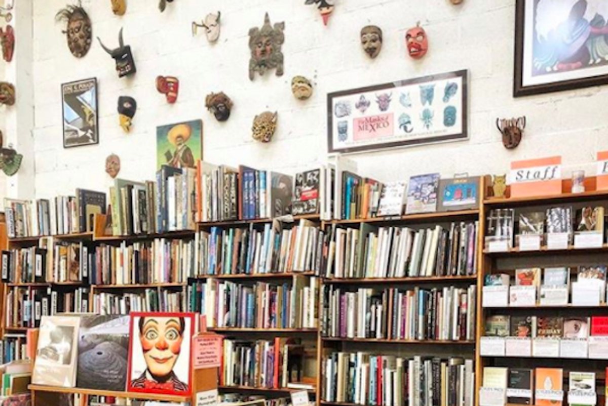 Bookshelves and colorful masks on a wall in a vibrant bookstore.