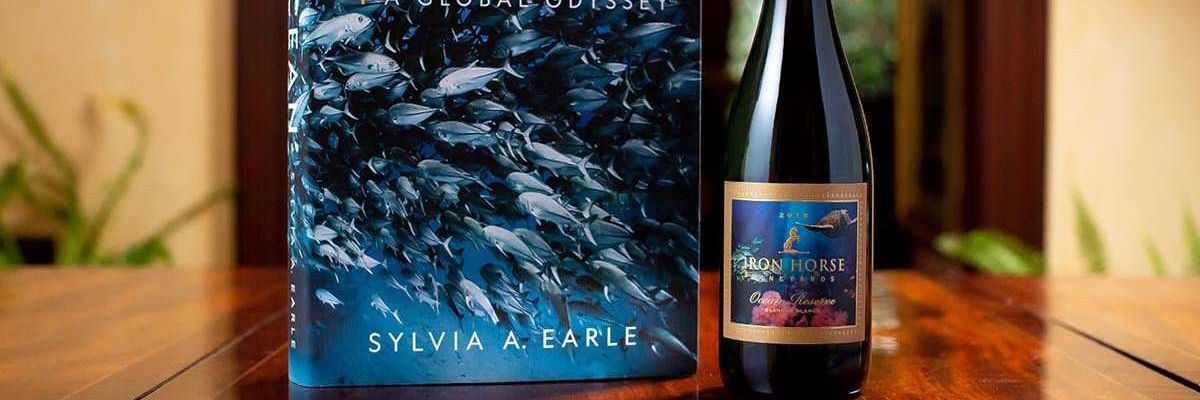 bottle of red wine from iron horse with a book by sylvia a earle on the ocean next to it