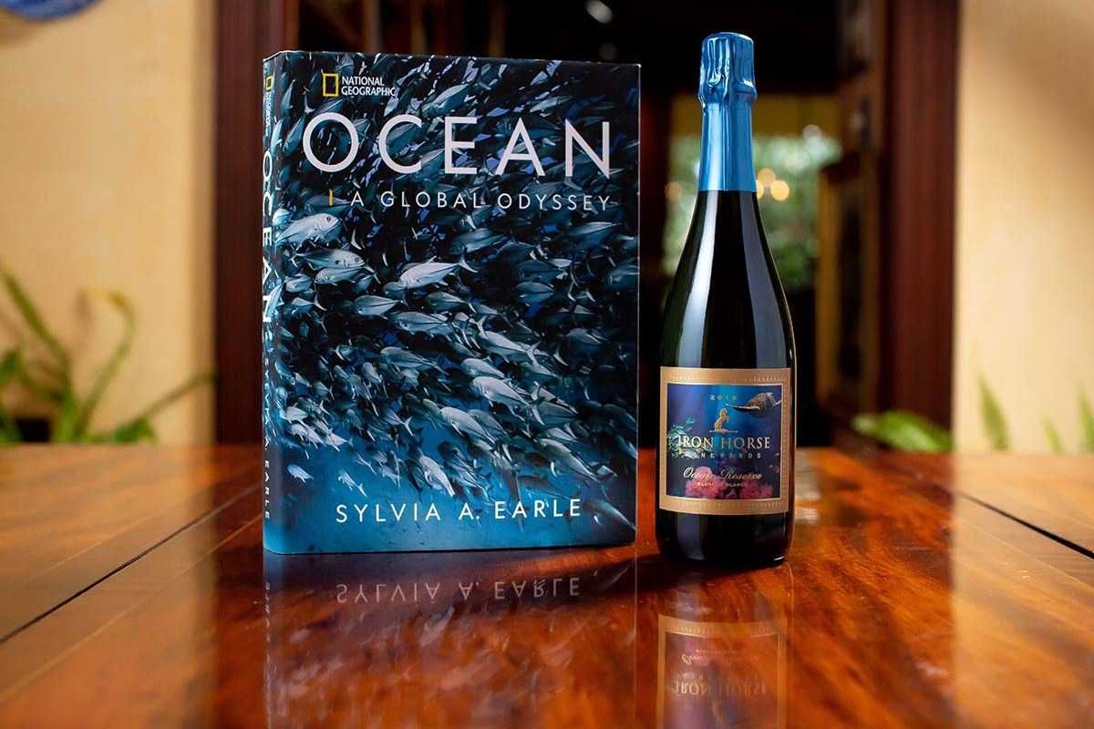 bottle of red wine from iron horse with a book by sylvia a earle on the ocean next to it