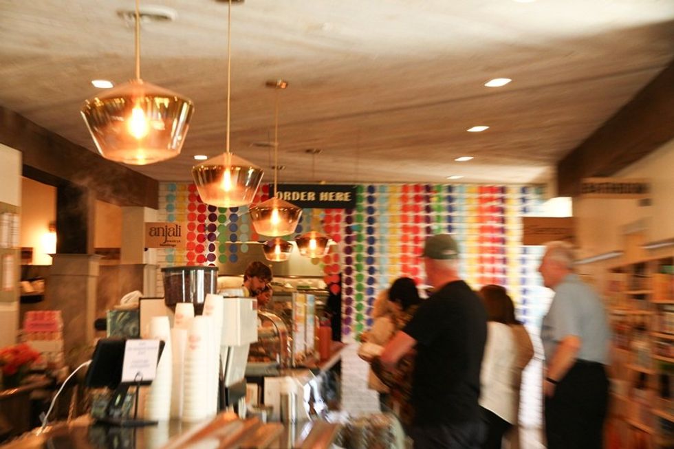 Cafe interior with blurred people, colorful dot wall, and hanging lights.