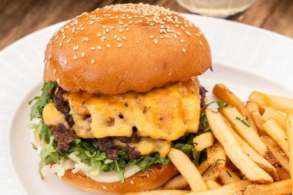 Cheeseburger with lettuce and fries on a white plate.