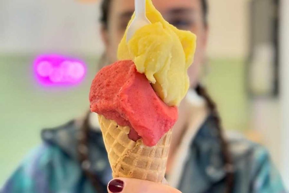Close-up of a waffle cone with yellow and red ice cream scoops.