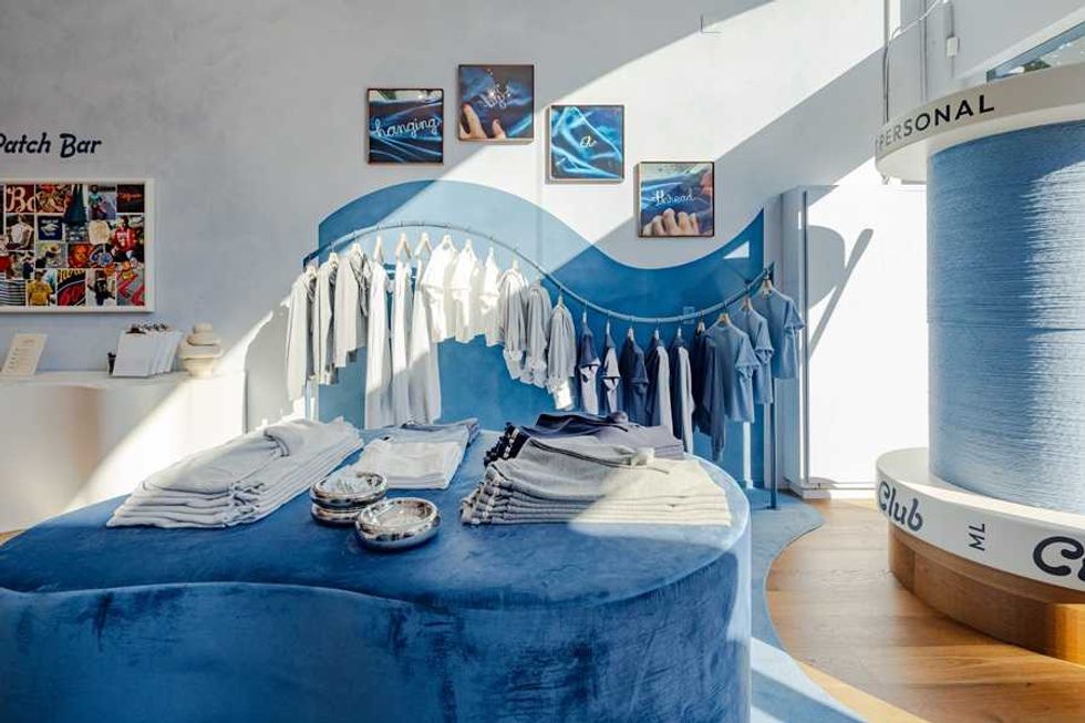 Clothing store with blue and white shirts, folded items, and decorative wall art.