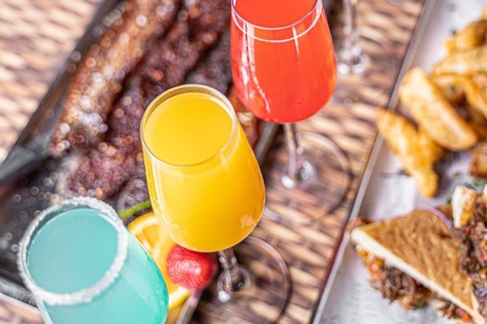 Colorful cocktails and assorted food on a table.