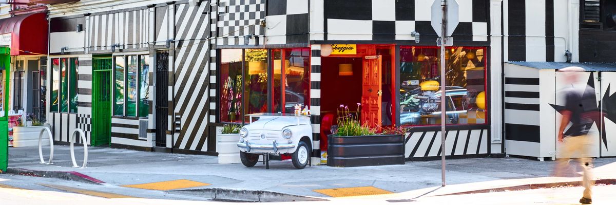 Colorful corner building with pink walls and black-and-white striped storefront.
