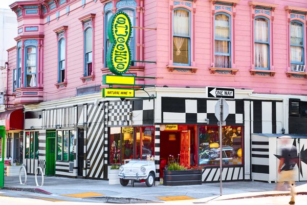 Colorful corner building with pink walls and black-and-white striped storefront.
