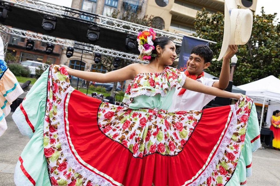 Couple in colorful traditional dress dancing outdoors.