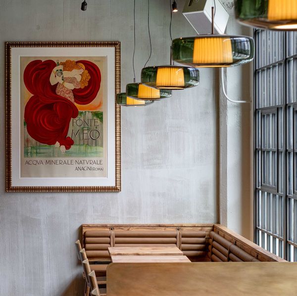 Cozy bar interior with vintage poster, wooden bar stools, and hanging lights.