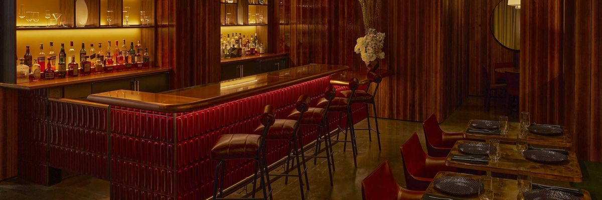 Cozy dimly-lit bar with warm wood accents and elegant glass shelving.