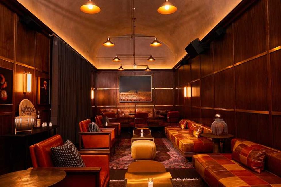 Cozy lounge with leather seating, warm lighting, and a wooden-paneled interior.