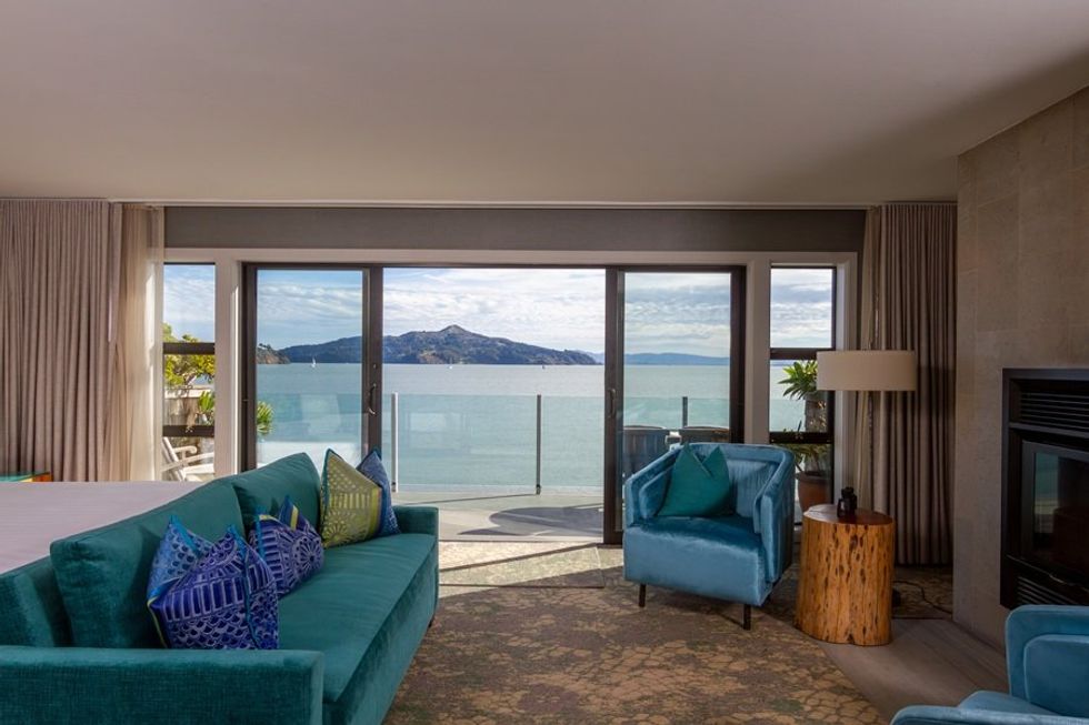Cozy room with teal sofa, ocean view through large window, and stylish decor.