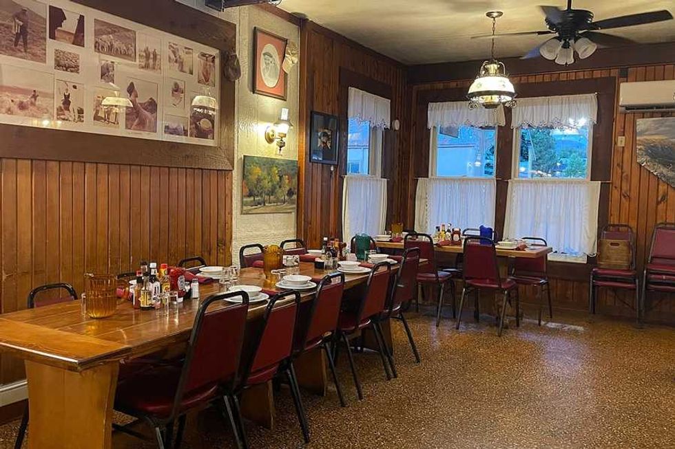 Cozy rustic dining room with long table, chairs, and wall art.