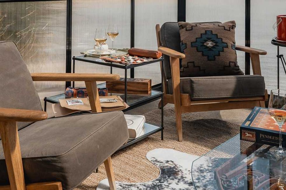 Cozy seating with armchairs, a patterned cushion, two wine glasses, and a game set on a table.