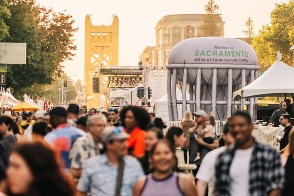 Crowded street festival in Sacramento with the Tower Bridge visible in the background.