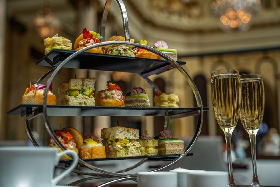 Elegant afternoon tea set with finger sandwiches and sparkling wine.