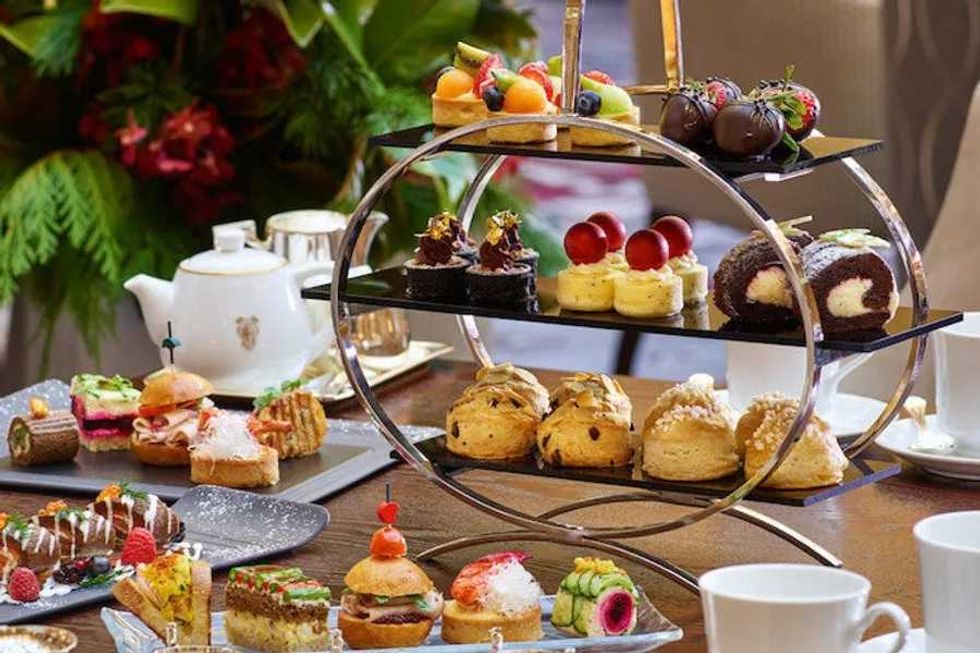 Elegant afternoon tea set with pastries, cakes, and scones on a tiered stand.