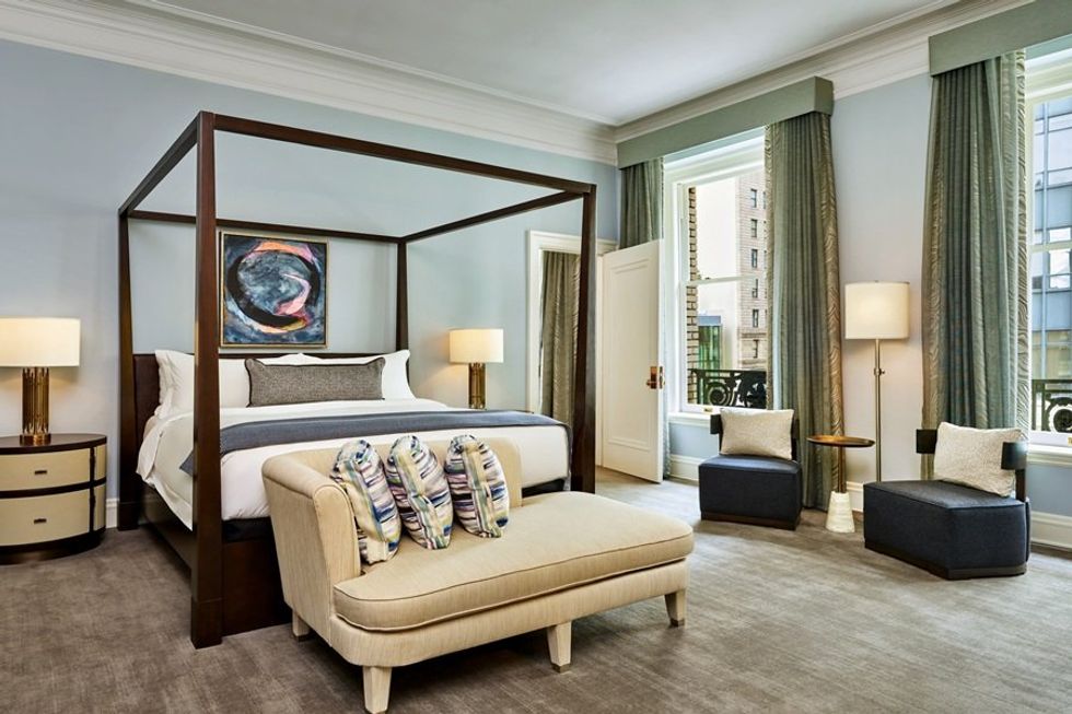 Elegant bedroom with a canopy bed, chaise lounge, and large windows with drapes.