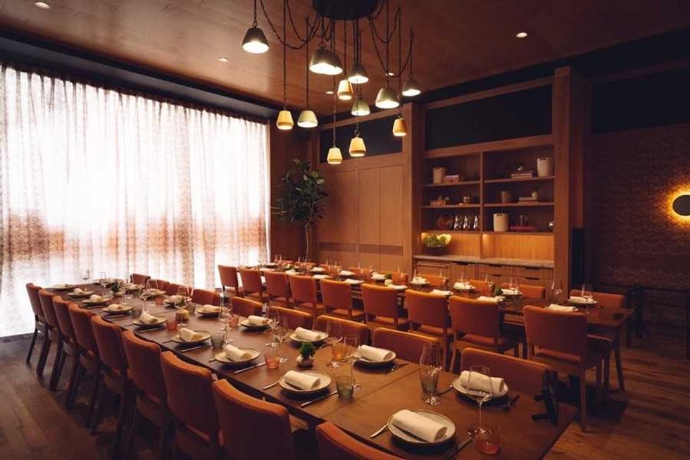 Elegant dining room with a long, set table, warm lighting, and wooden decor.
