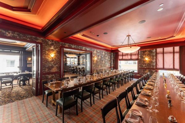 Elegant dining room with long tables set for a formal dinner, warm lighting, and red decor.